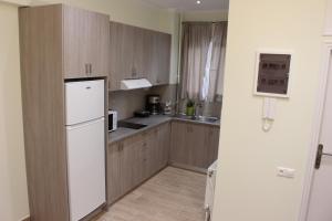 a kitchen with wooden cabinets and a white refrigerator at Comfortable apartment in the center of Athens in Athens