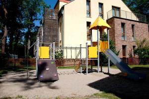 a playground in front of a house with a slide at Apartament IKAR z ogródkiem, blisko morza in Rewal
