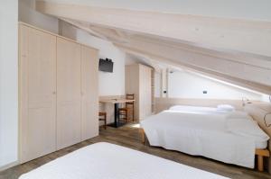 a bedroom with a large white bed and a desk at Affittacamere La Ferrata in San Michele allʼAdige