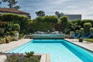 uma piscina num jardim com duas cadeiras em Chambre d'Hôtes Etchebri em Anglet