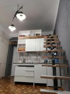 リヴィウにあるКвартира ЛОФТ 2 во Львовеの白いキャビネット付きのキッチン、階段