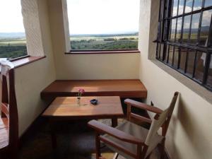 a small table and two chairs in a room with a window at Mwanzo Lodge in Naivasha