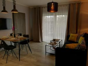 uma sala de estar com uma mesa e um sofá em Coral SPA Apartament Pięć Mórz em Sianozety