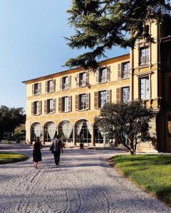 dos personas caminando por un camino en frente de un edificio en Villa Biondelli Wine & Suites en Cazzago San Martino