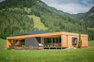 ein Haus auf einem Feld mit Bergen im Hintergrund in der Unterkunft Stoaberg Lodge in Sankt Ulrich am Pillersee