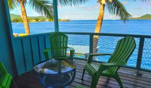 2 Stühle und ein Tisch auf einer Veranda mit Meerblick in der Unterkunft Sunset Hill Lodge in Bora Bora
