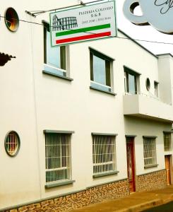 a white building with a sign in front of it at Pizzeria Colisseo B & B in Jinotepe