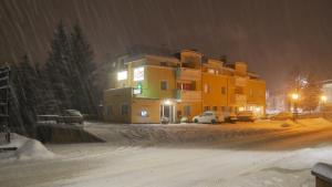 una calle cubierta de nieve con un edificio en el fondo en Appartmenthotel Residence Elvis en Ortisei