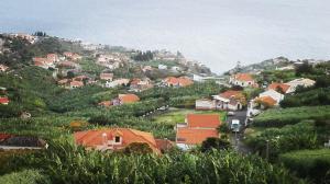 a village on a hill with houses and the ocean at Appartamento Villa in Ponta do Sol