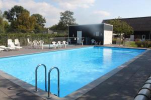 a large blue swimming pool with chairs and a building at Holiday cottage with sauna in Zeeland in Stavenisse
