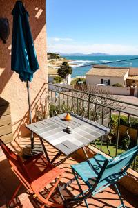 ein Tisch und zwei Stühle und ein Sonnenschirm auf dem Balkon in der Unterkunft A 2 pas de la Mer in Sausset-les-Pins