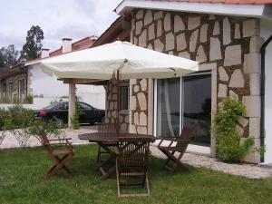 a table and chairs under an umbrella in front of a house at Casas Da Azenha in Vila Nova de Cerveira