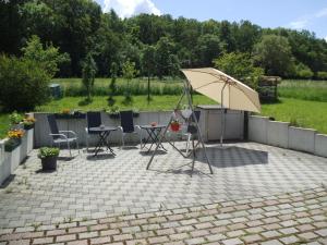 um pátio com um guarda-sol, uma mesa e cadeiras em Pension Rammert em Großbettlingen