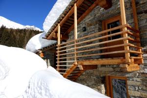 a log cabin in the snow with a wooden staircase at Lavarets Chambres d’Hôtes in Ayas