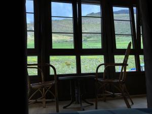 two chairs and a table in front of a window at Valle del sol II in Pajares