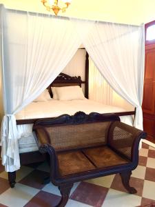 a bedroom with a canopy bed with a chair at THE VILLAS at THE HORNED DORSET PRIMAVERA in Rincon