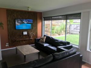 a living room with a black leather couch and a table at BEACHPOINT COTTAGE in Warrnambool
