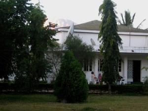 una casa blanca con dos personas sentadas frente a ella en Kitolie Home and Lodge en Moshi