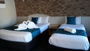 two beds in a hotel room with towels on them at Country Gardens Motor Inn in Toowoomba