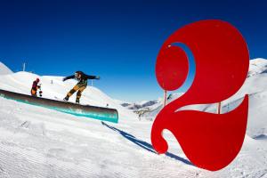 a man riding a snowboard down a snow covered slope at Studio les deux alpes Résidence le Pluton B84 WIFI in Les Deux Alpes