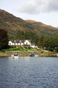 un groupe de bateaux dans l'eau devant une maison dans l'établissement Ardlui Hotel, à Ardlui