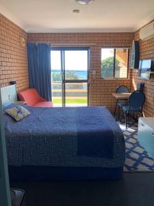 a bedroom with a bed and a large window at Whale Fisher Motel in Eden