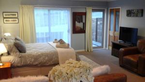 um quarto com uma cama, uma televisão e um sofá em Pukeko Nest em Russell