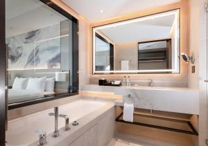 a bathroom with a tub and a large mirror at Carlton Hotel Bangkok Sukhumvit - SHA Extra Plus in Bangkok