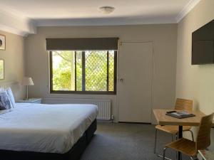 a bedroom with a bed and a desk and a window at Jindy Inn in Jindabyne