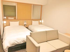 富良野La Vista Furano Hills Natural Hot Spring的有两张床和一把椅子的房间