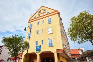 ibis budget Singapore Joo Chiat في سنغافورة: مبنى أصفر عليه علامة زرقاء