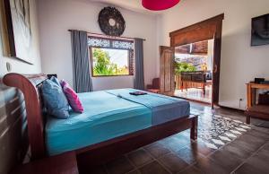 a bedroom with a bed with blue sheets and a window at Villa Bukit Malas 3 in Amed