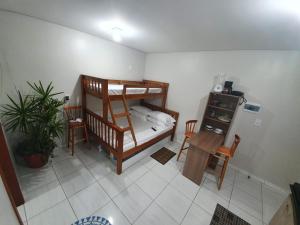 Kitnet Praia da Vila Imbituba في إيمبيتوبا: غرفة بسرير بطابقين وطاولة وكراسي