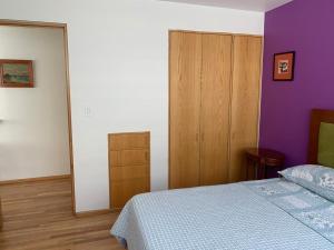 a bedroom with a bed and a purple wall at Departamentos Pánuco in Mexico City