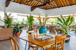 une salle à manger avec une table, des chaises et des plantes dans l'établissement Akaya Bali, à anur