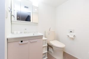 a white bathroom with a toilet and a sink at Cross Bridge Ikebukuro in Tokyo