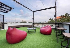 un patio en la azotea con sillas, mesas y césped en LOBSUEK Hostel หลบศึก โฮสเทล, en Bangkok