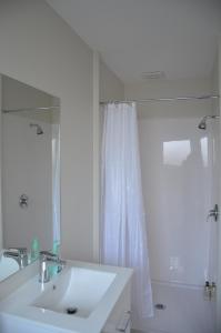 a white bathroom with a sink and a mirror at Judges Pool Motel Turangi in Turangi