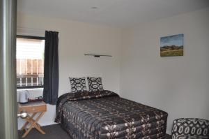 a bedroom with a bed and a table and a window at Judges Pool Motel Turangi in Turangi