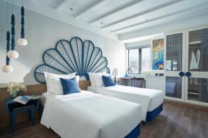 two beds in a room with white walls and blue accents at Sofiana My Khe Hotel & Spa- Rooftop Pool Bar in Danang