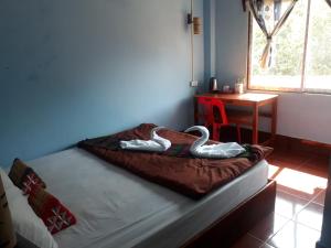 a bed with two swans on it in a room at Lamorn Guesthouse in Nongkhiaw