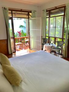 a bedroom with a large white bed and a balcony at Mali House in Mae Nam