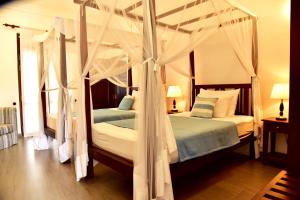 - une chambre avec 2 lits dotés de rideaux blancs dans l'établissement Boutique Villa Shanthi, à Hikkaduwa
