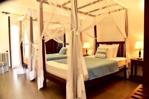 a bedroom with two beds with white drapes at Boutique Villa Shanthi in Hikkaduwa