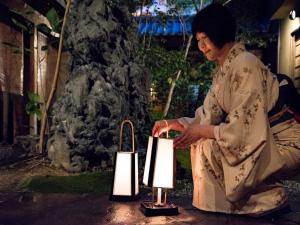 Una donna seduta accanto a una lanterna in un giardino di Yamatoya Besso a Matsuyama