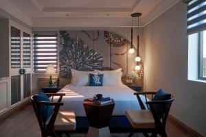 a bedroom with a bed with two chairs and a table at Sofiana My Khe Hotel & Spa- Rooftop Pool Bar in Danang