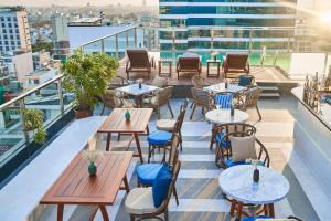 a patio with tables and chairs on a balcony at Sofiana My Khe Hotel & Spa- Rooftop Pool Bar in Danang