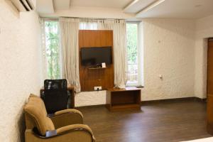 a living room with a flat screen tv and chairs at Mrugavani Resort & Spa in Hyderabad