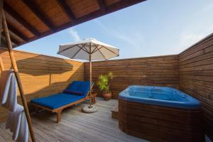 uma banheira de hidromassagem, uma cadeira e um guarda-sol num deque em Vilamendhoo Island Resort & Spa em Dhangethi