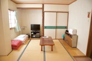 uma sala de estar com uma mesa e uma televisão em City Pension Tommy Rich Inn Kyoto em Quioto